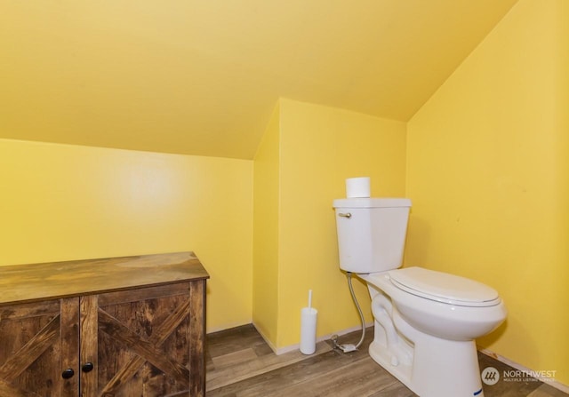 bathroom featuring hardwood / wood-style floors, toilet, and vaulted ceiling