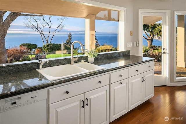 kitchen featuring a water view, white dishwasher, plenty of natural light, sink, and white cabinetry