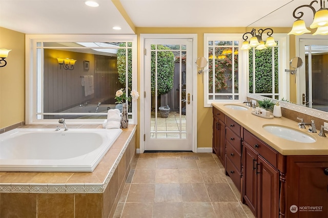 bathroom featuring vanity, a chandelier, and a relaxing tiled tub