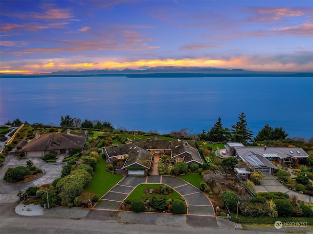 aerial view at dusk featuring a water view