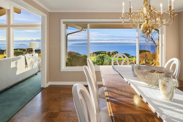 dining area featuring dark parquet flooring, crown molding, a chandelier, and a water view