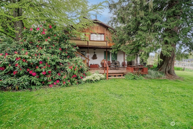 back of property featuring a deck and a lawn