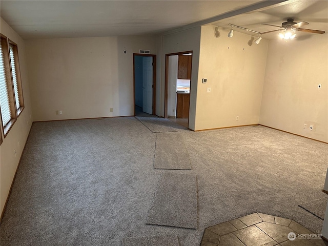 empty room featuring carpet floors, track lighting, and ceiling fan