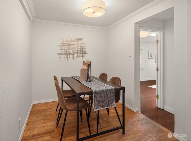 dining space with hardwood / wood-style flooring and crown molding