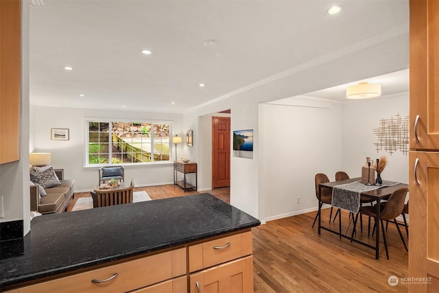 kitchen featuring ornamental molding, light hardwood / wood-style flooring, and dark stone countertops