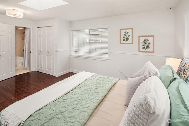 bedroom featuring a skylight, connected bathroom, and hardwood / wood-style flooring