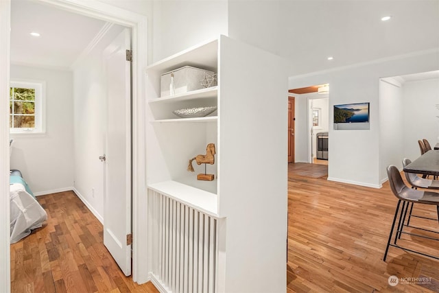 corridor featuring ornamental molding and light hardwood / wood-style floors