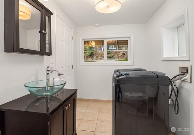 laundry area with sink, light tile patterned flooring, hookup for a washing machine, and cabinets