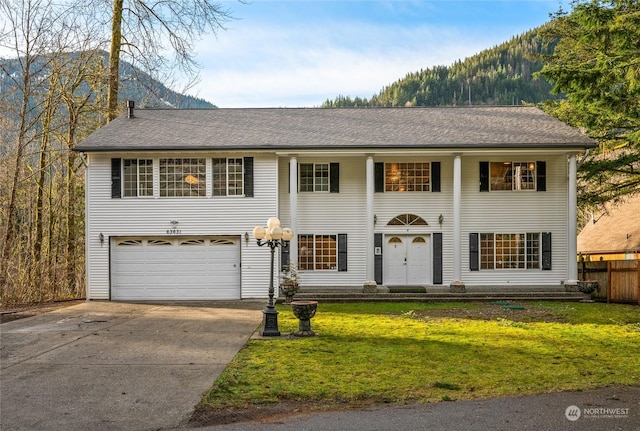 view of front of property with a mountain view, a front lawn, and a garage