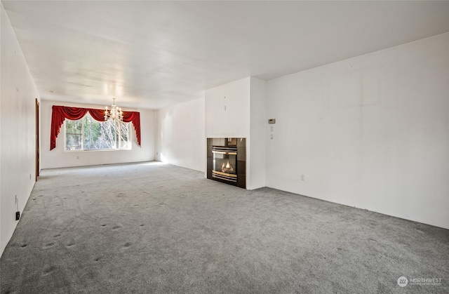 unfurnished living room featuring a tile fireplace, carpet floors, and a chandelier