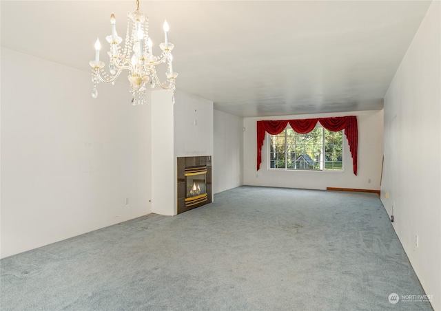 unfurnished living room with a tiled fireplace, light carpet, and a chandelier