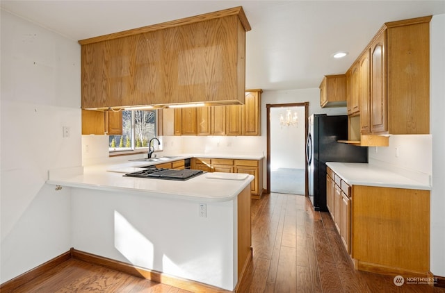 kitchen featuring stainless steel gas stovetop, wood-type flooring, kitchen peninsula, and sink