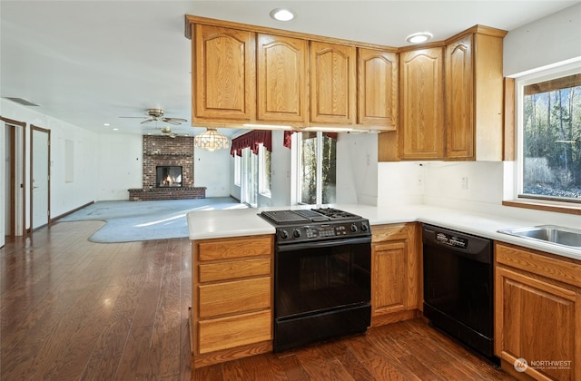 kitchen with black appliances, dark hardwood / wood-style floors, a healthy amount of sunlight, and a fireplace