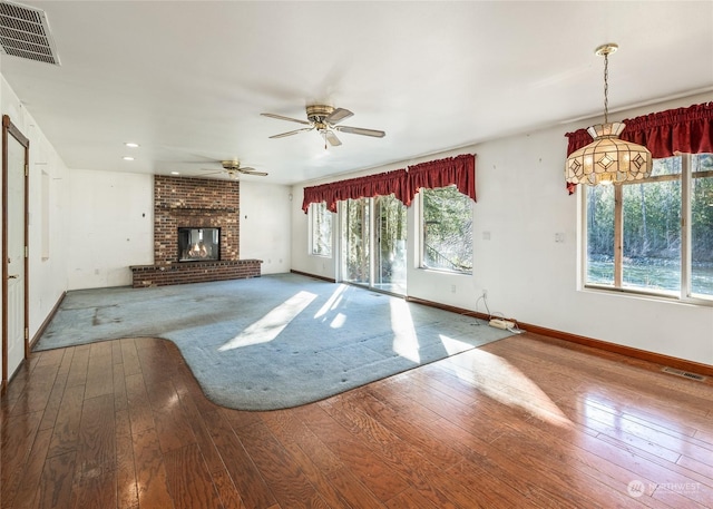 unfurnished living room featuring hardwood / wood-style floors, ceiling fan, and a fireplace