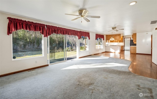 unfurnished living room featuring ceiling fan and carpet floors