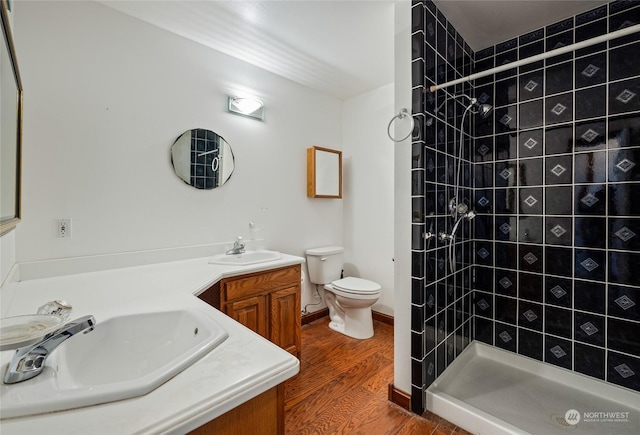 bathroom with a tile shower, vanity, hardwood / wood-style flooring, and toilet