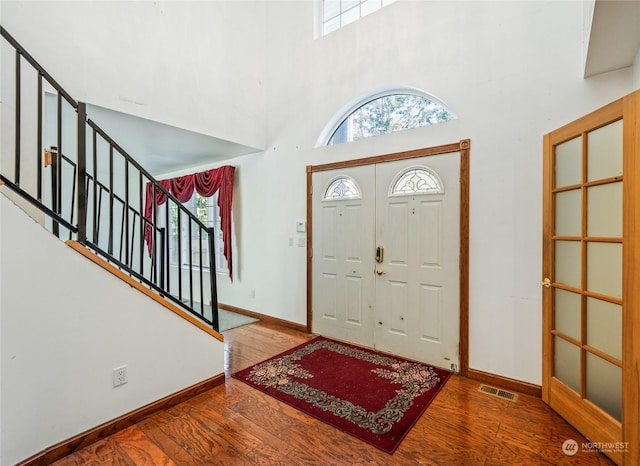 entrance foyer with wood-type flooring and a towering ceiling