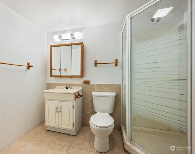 bathroom with tile patterned floors, walk in shower, vanity, tile walls, and toilet