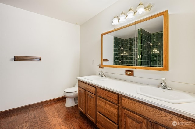 bathroom with tiled shower, toilet, vanity, and hardwood / wood-style flooring