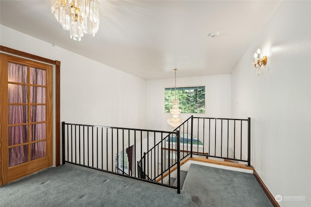 hallway with carpet floors and a notable chandelier