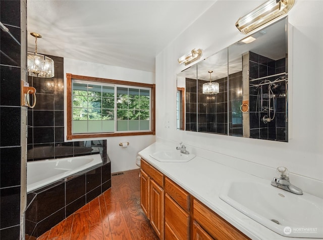 bathroom with vanity, a relaxing tiled tub, wood-type flooring, and a notable chandelier