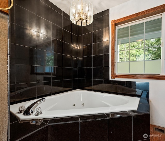 bathroom with a relaxing tiled tub and a chandelier