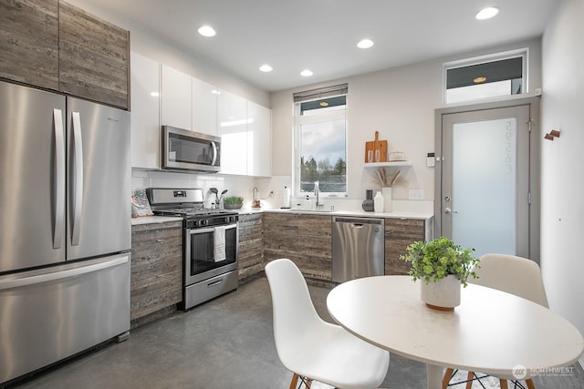 kitchen with white cabinets, backsplash, stainless steel appliances, and sink