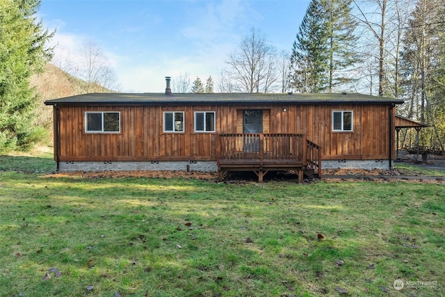 rear view of property featuring a deck and a yard