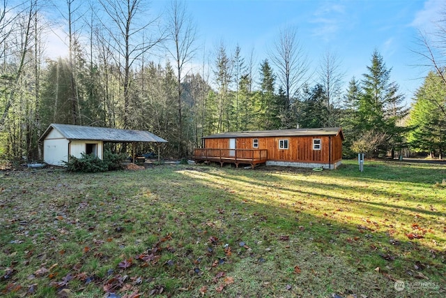 exterior space with a lawn, an outbuilding, and a wooden deck