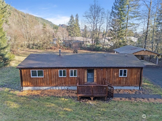 back of property with a lawn and a deck with mountain view