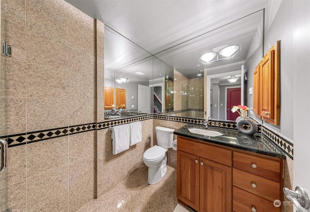 bathroom with vanity, toilet, walk in shower, and tile walls