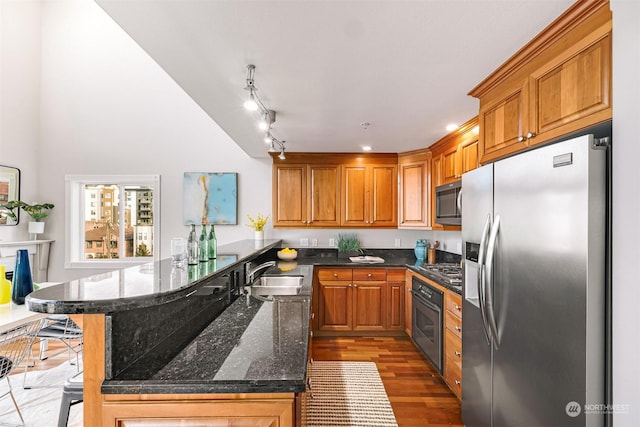 kitchen featuring kitchen peninsula, stainless steel appliances, sink, light hardwood / wood-style flooring, and a breakfast bar area