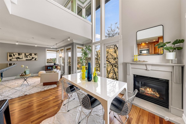 dining space with light wood-type flooring, a high ceiling, and ornamental molding