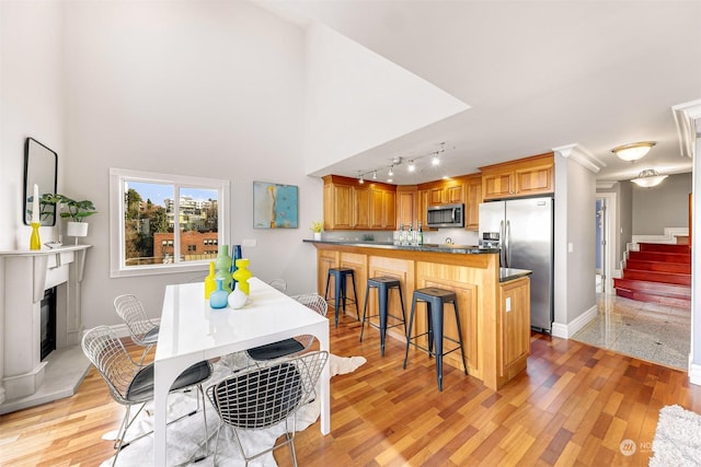 kitchen featuring a kitchen bar, kitchen peninsula, stainless steel appliances, and light hardwood / wood-style floors