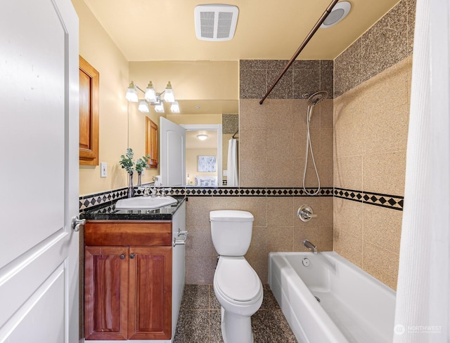 full bathroom featuring tiled shower / bath combo, tile patterned floors, toilet, vanity, and tile walls