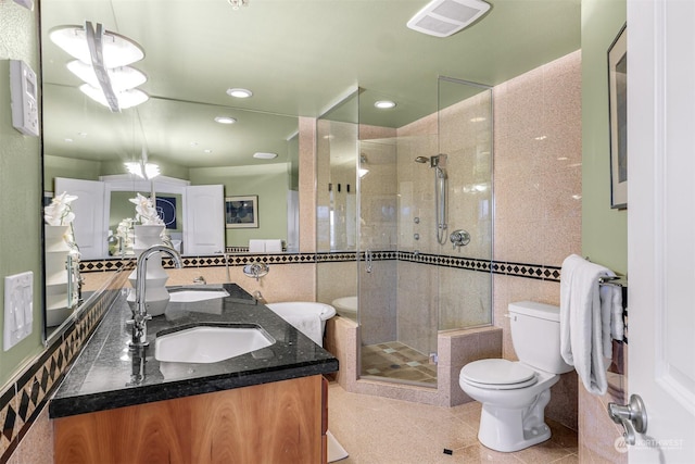 bathroom featuring vanity, a shower with door, tile patterned flooring, toilet, and tile walls