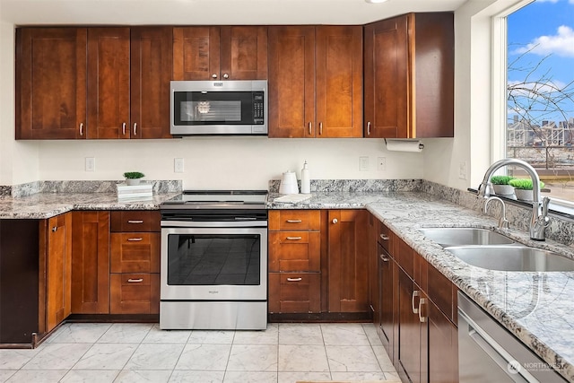 kitchen with light stone countertops, stainless steel appliances, a healthy amount of sunlight, and sink