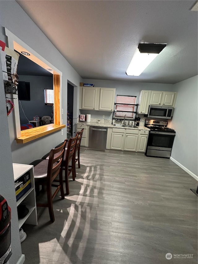 kitchen with hardwood / wood-style flooring, sink, appliances with stainless steel finishes, and cream cabinets