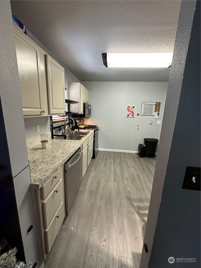 kitchen with sink, light wood-type flooring, a textured ceiling, and appliances with stainless steel finishes