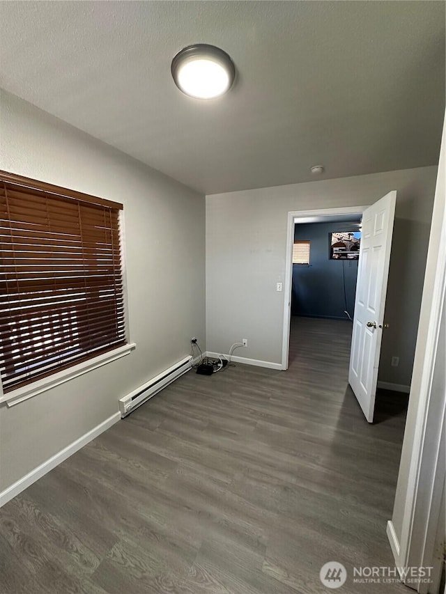 laundry area featuring a baseboard radiator, baseboards, and wood finished floors