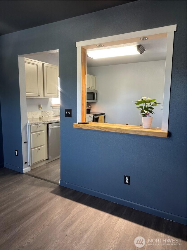 kitchen with light countertops, wood finished floors, appliances with stainless steel finishes, and baseboards