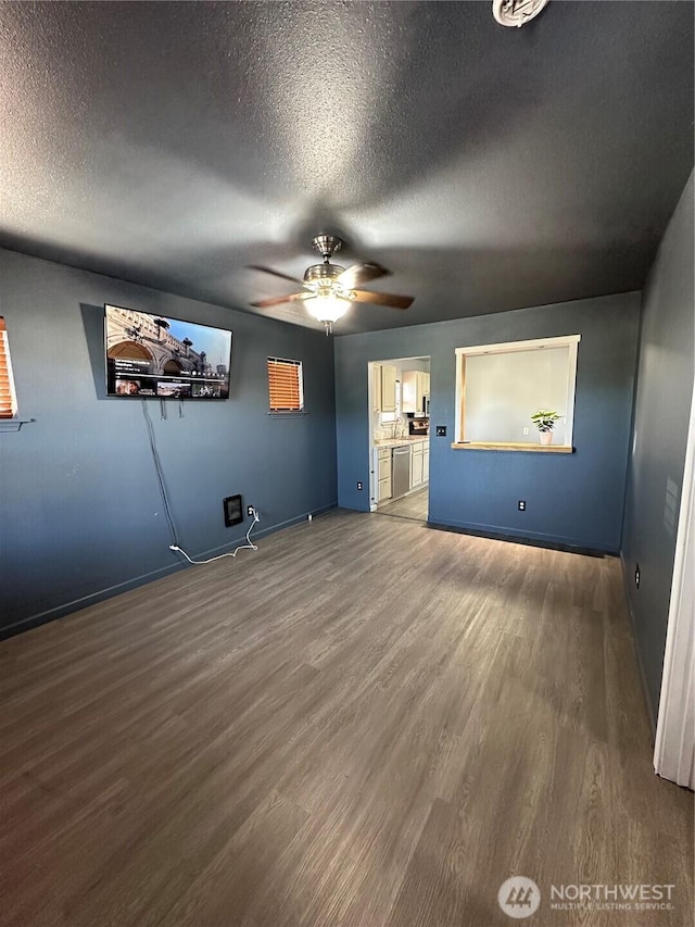 interior space featuring baseboards, a ceiling fan, wood finished floors, and a textured ceiling