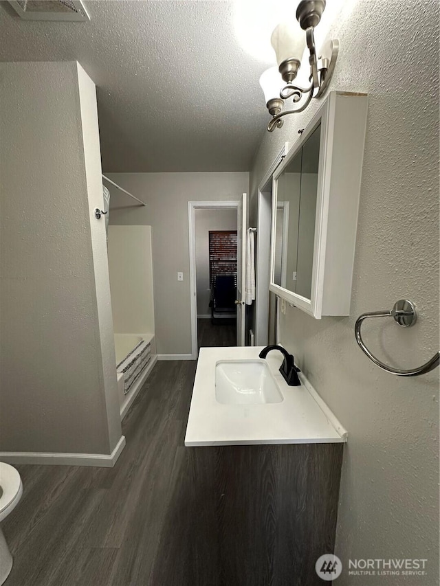 full bath featuring a textured ceiling, a sink, baseboards, wood finished floors, and a shower