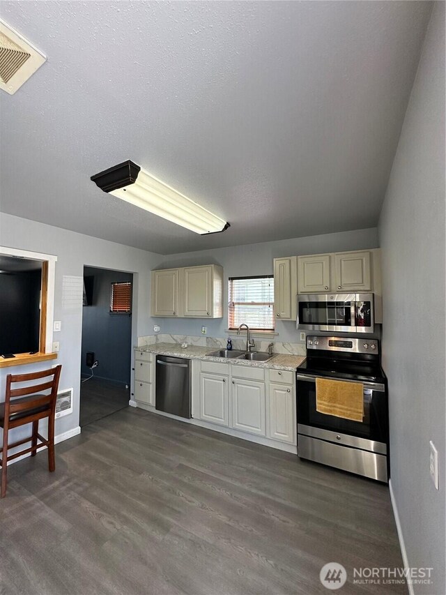 kitchen with stainless steel appliances, a sink, dark wood-style flooring, baseboards, and visible vents