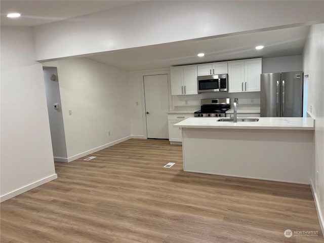 kitchen featuring white cabinetry, sink, stainless steel appliances, and light wood-type flooring