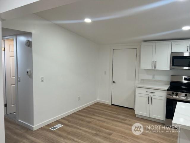 kitchen featuring stainless steel appliances, white cabinets, and light wood-type flooring