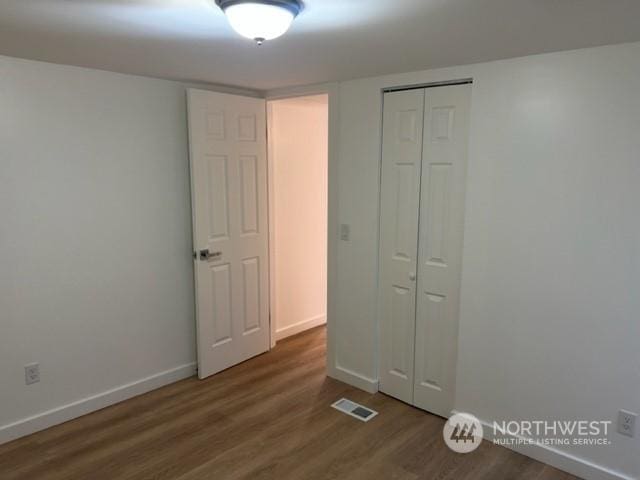 unfurnished bedroom featuring dark hardwood / wood-style flooring and a closet