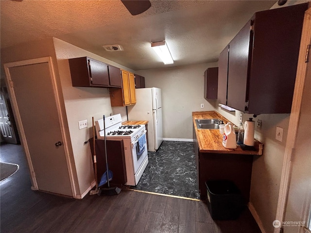 kitchen featuring a textured ceiling, white appliances, dark wood-type flooring, and sink