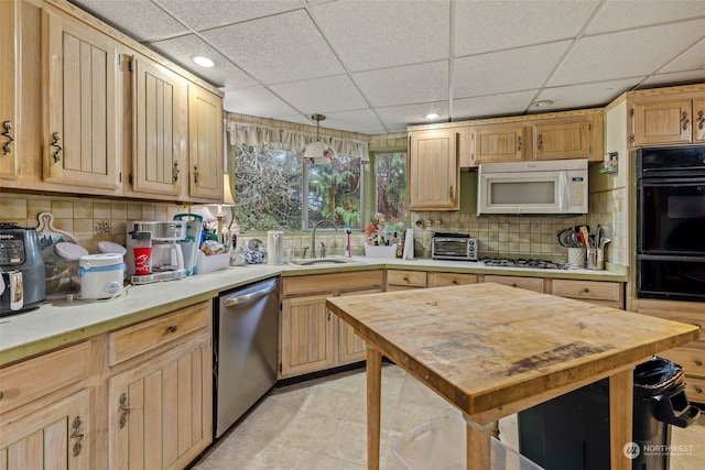 kitchen with appliances with stainless steel finishes, tasteful backsplash, sink, hanging light fixtures, and a drop ceiling