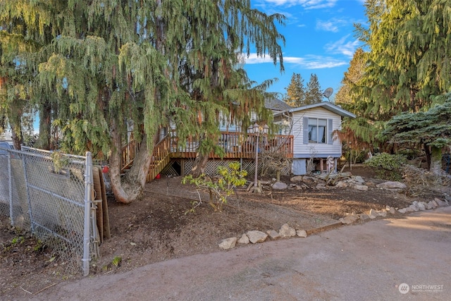 view of property hidden behind natural elements with a wooden deck